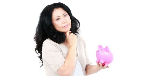 Thoughtful asian woman holding pink piggy bank