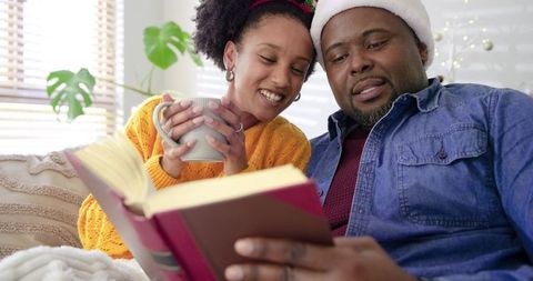 Couple reading together on sofa sharing book during cozy holiday morning