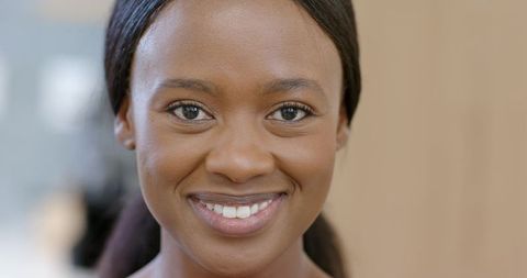 Confident african woman smiling making eye contact warm studio headshot soft lighting