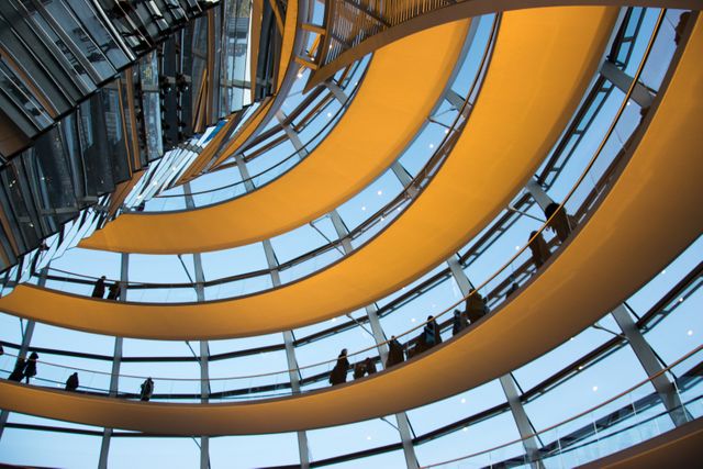 This image showcases a spectacular modern building interior featuring concentric spiral walkways made of glass and steel. The geometric patterns and reflections within the structure create a visually compelling scene that highlights contemporary design and engineering innovation. Suitable for use in architectural magazines, corporate presentations, urban planning materials, and design blogs.