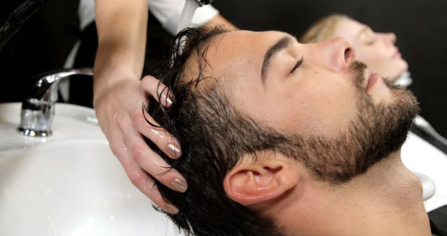 Man Receiving Hair Wash at Salon with Female in Background - Download Free Stock Images Pikwizard.com