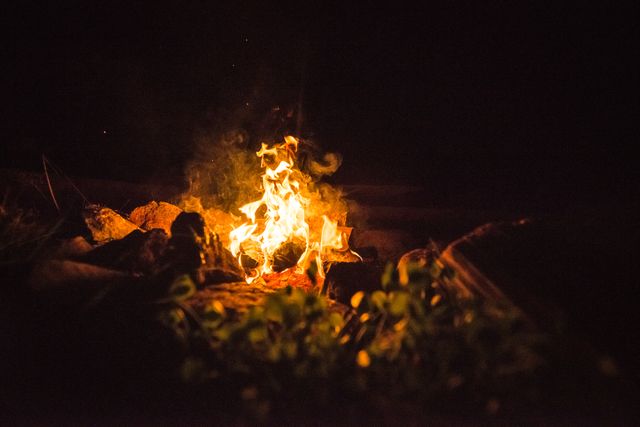 Campfire burning brightly in the night. Perfect for themes related to camping, outdoor adventures, wilderness survival, relaxation, and nature trips. Ideal for use in blogs, social media posts, travel websites, and outdoor recreation promotions.