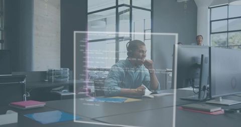 Developer debugging code on large monitor in modern open office with headset