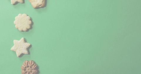 Assorted sugar-dusted cookies lining left on mint green backdrop with plenty of copy space