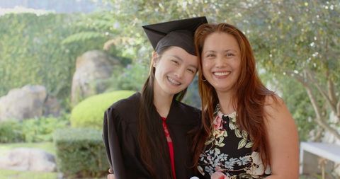Proud Mother and Graduate Daughter Embracing in Celebration Outdoors