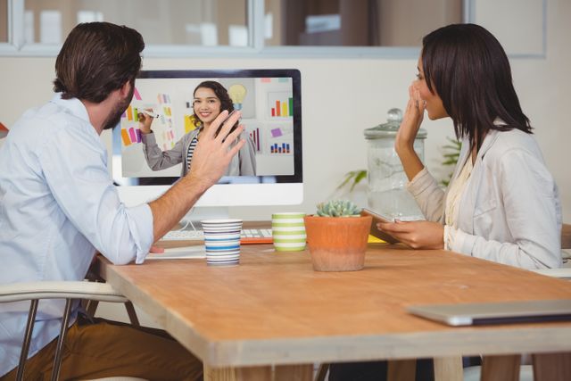 Colleagues are engaged in a video conference in a modern office. This scene depicts remote work and effective team collaboration using technology. Useful for articles or advertisements on virtual meetings, remote teamwork, communication tools, or modern offices.