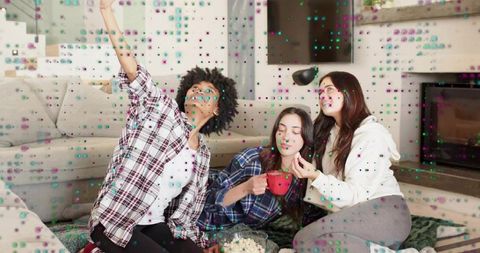 Three friends taking selfie on cozy living room rug sharing popcorn and warm cocoa