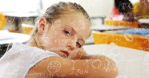 Pensive schoolgirl resting on desk with chemistry formulas overlay for learning concept