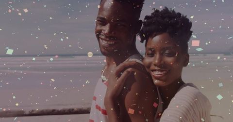 Romantic Couple Smiling on Beach with Confetti Celebration