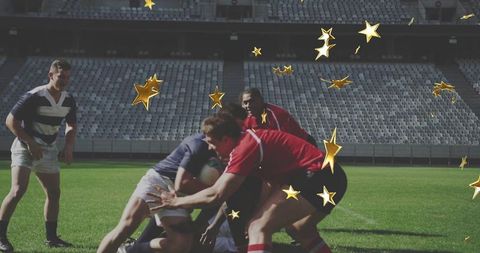 Tackling rugby players in red and blue jerseys executing intense ruck with golden stars