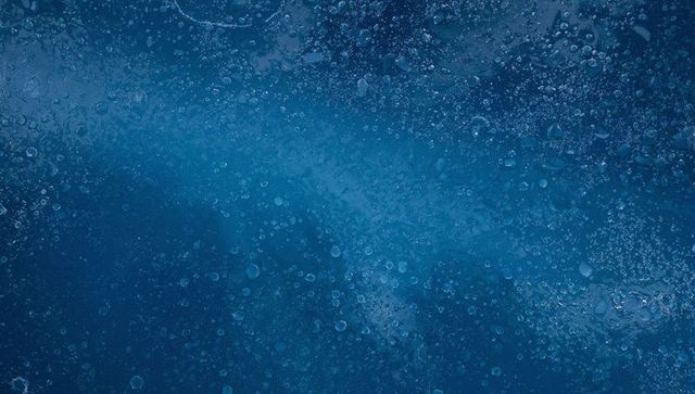 Macro ice texture with trapped air bubbles and crystalline frost in deep blue gradient