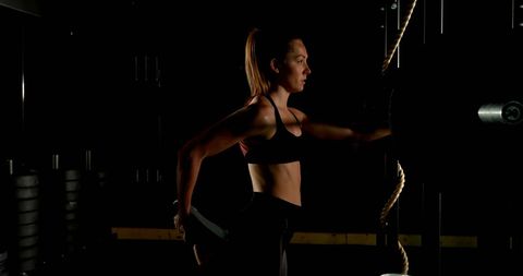 Female Athlete Stretching in Dimly Lit Gym