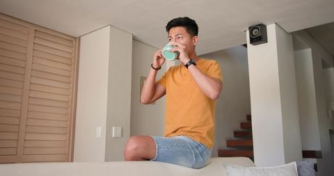 Asian Man Relaxing at Home with Mint-Green Mug