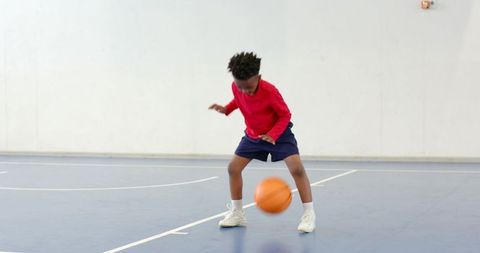 Young Boy Dribbling Basketball on Indoor Court
