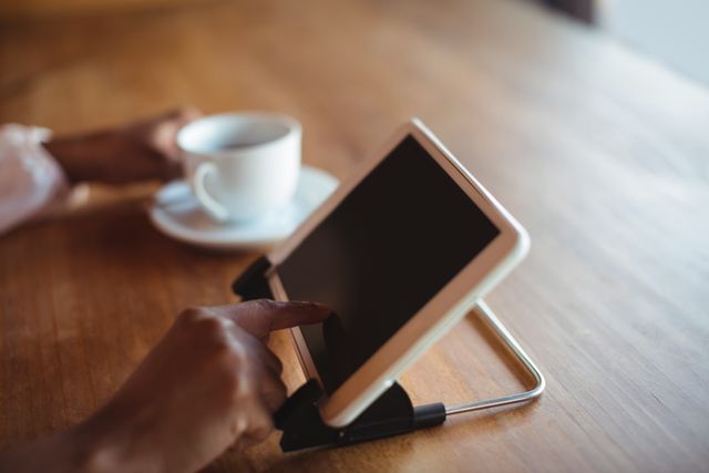 Hands of woman using digital tablet while having coffee in restaurant