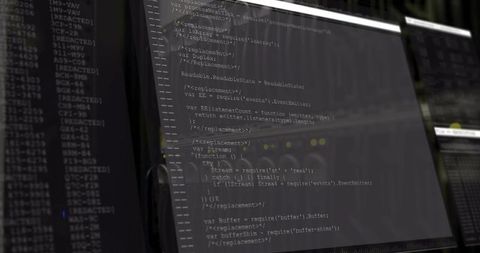 Javascript code displayed on office monitors with dim lighting