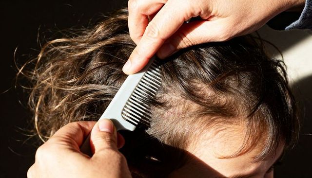 Caregiver combing child's brown hair revealing scalp closeup with light-grey comb