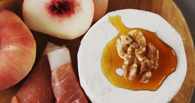 Red peaches, thin slices of prosciutto, and brie topped with honey and walnut create a gourmet appetizer perfect for a sophisticated snack or charcuterie board. Ideal for food blogs, culinary magazines, or social media posts promoting food-related content.