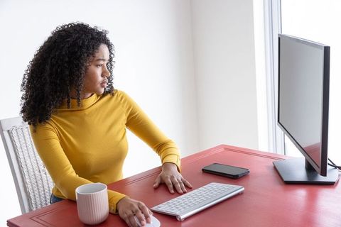 African American Woman Working at Red Desk with Monitor in Home Office