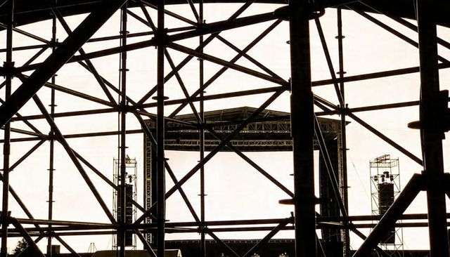 Scaffolding grid framing open-air concert stage silhouette with truss and speaker stacks