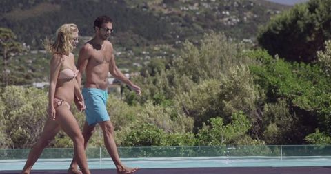 Couple Strolling by Infinity Pool on Serene Day