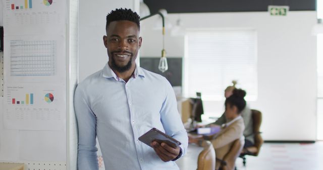 Portrait of happy african american businessman with tablet in creative office. business and finances in creative office.