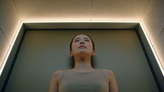 Contemplative asian woman standing in led-framed alcove with minimalist symmetrical design
