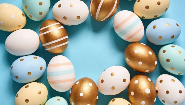 Pastel and Gold Easter Egg Wreath Forming Circular Frame on Bright Blue Backdrop
