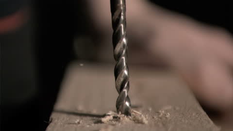 Close-Up of Drill Penetrating Wooden Plank in Slow Motion