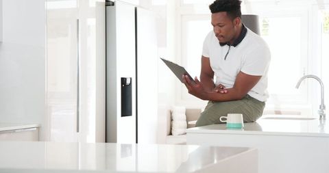 Man writing on clipboard in modern kitchen with natural light