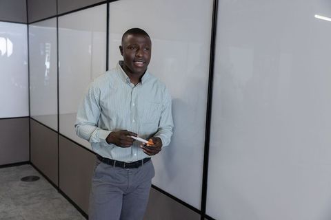 Businessman standing with markers by glass panels for corporate presentation