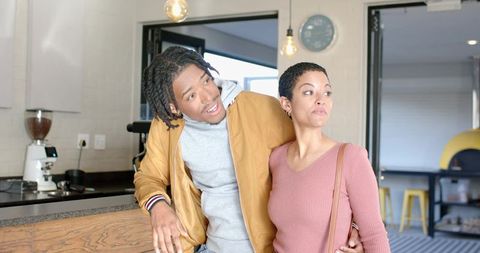 Young diverse couple leaning at cafe counter sharing candid moment near espresso machine