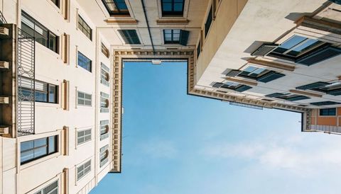 Sunlit narrow courtyard framing clear blue sky between european facades and shutters