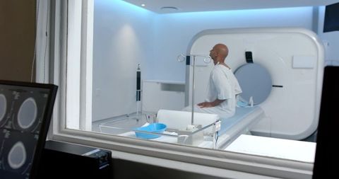 African american man sitting on ct scanner table in hospital radiology preparing for brain scan