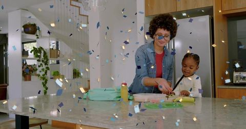 Guiding woman preparing snacks with child on marble island amid confetti