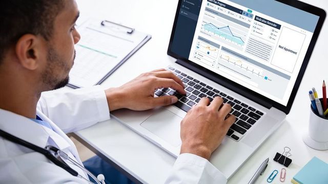 Doctor typing on laptop analyzing electronic health record dashboard with vitals and medication remi