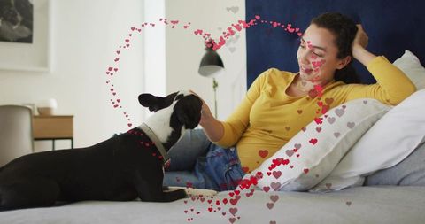 Woman relaxing on bed petting dog surrounded by heart overlays cozy indoor bonding