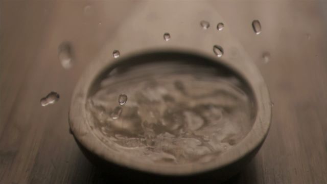 Water drops captured in super slow motion, creating mesmerizing ripples in a wooden spoon. Useful for illustrating concepts of fluid dynamics, kitchen-related articles, or ads emphasizing precision in cooking. Effective for educational videos, blogs about kitchen aesthetics, or commercial advertisements for utensils.