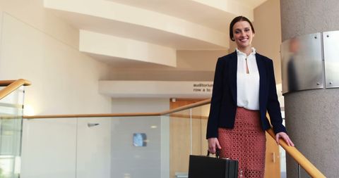 Confident Businesswoman Holding Briefcase in Modern Office - Download Free Stock Images Pikwizard.com