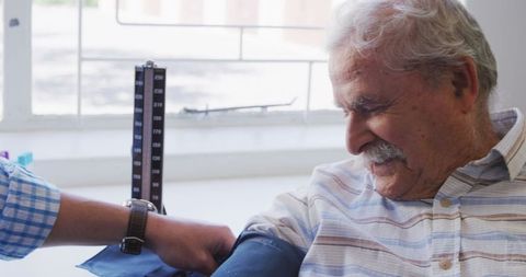 Senior man receiving blood pressure checkup amid covid-19