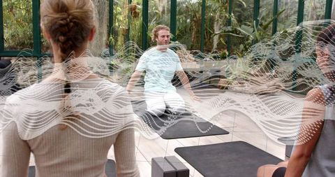 Yoga class in glass greenhouse with instructor leading mindfulness and breathwork among plants