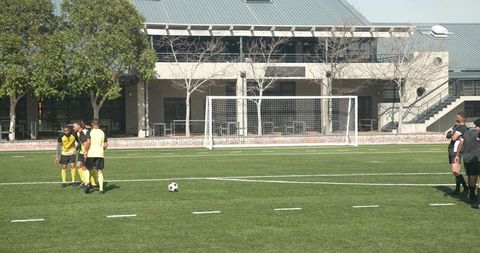 Soccer Players Strategizing Near Goal on School Field