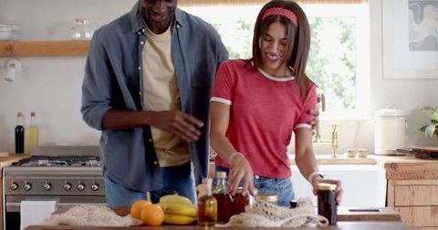 Happy Couple Organizing Fresh Produce and Jars in Bright Kitchen