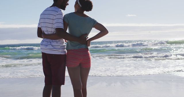 African american couple smiling and embracing on the beach. healthy outdoor leisure time by the sea.