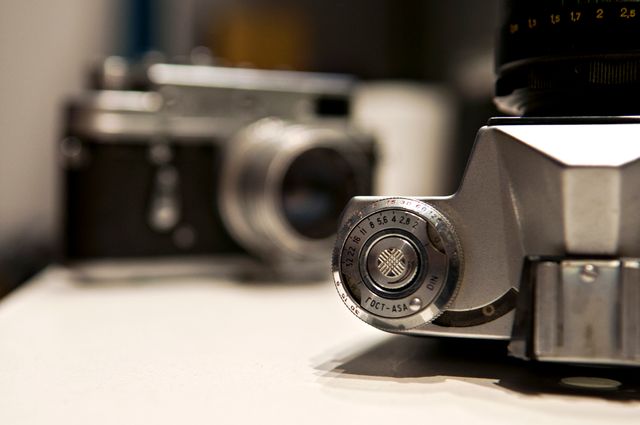 Close-up of vintage film cameras showcasing the details of the aperture settings. Ideal for use in articles, blog posts, and advertisements about photography, vintage equipment, or technology history.