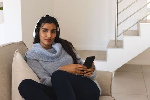 Relaxed Woman Listening to Music on Sofa with Smartphone and Headphones