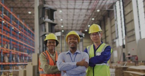 Confident warehouse team in hard hats and safety vests at modern distribution center