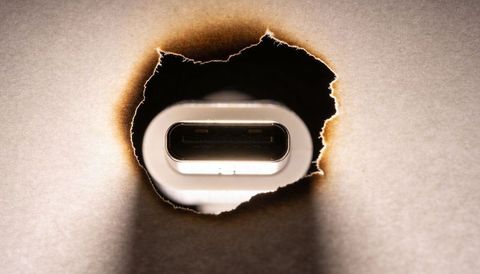 Revealing usb-c port through charred paper hole, macro closeup with dramatic shadow