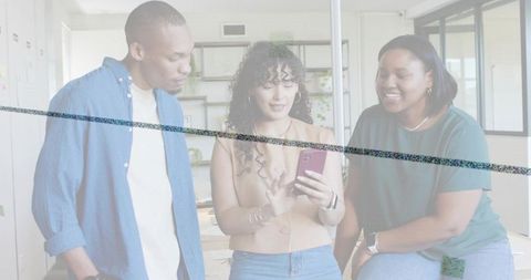 Diverse team collaborating around smartphone in bright modern coworking workspace