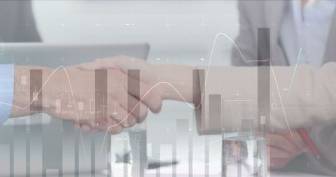 Business partnership sealed with handshake amid financial data graphics